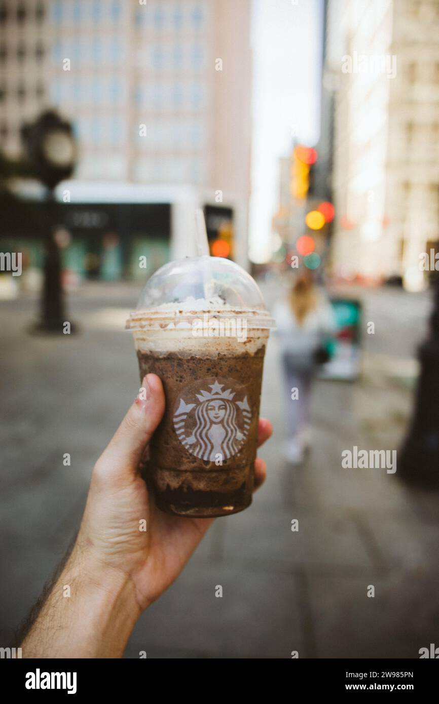 Eine Hand, die einen Kaffee mit Starbucks Logo hält Stockfoto