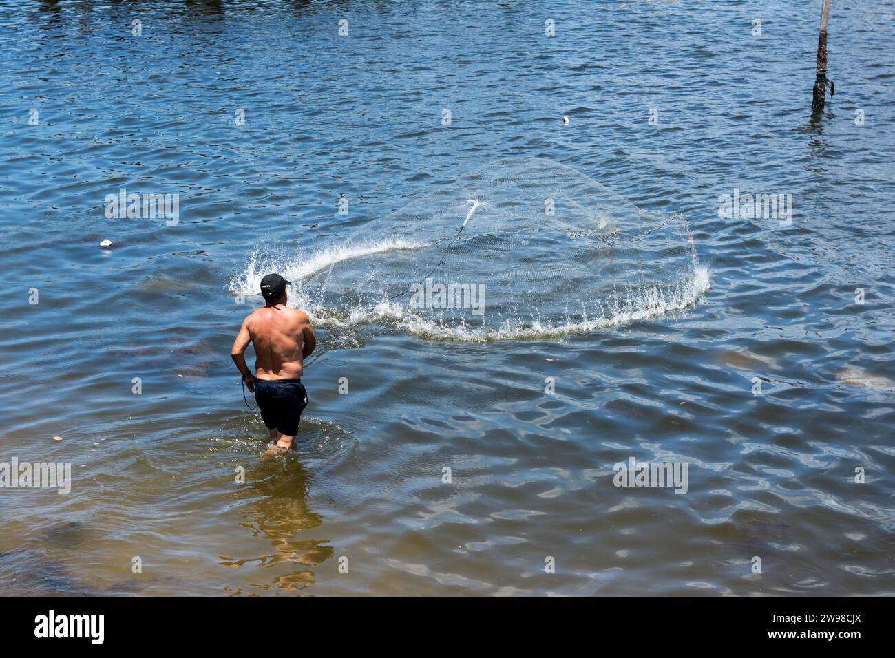 Salvador, Bahia, Brasilien - 18. Januar 2015: Ein Mann, ein Fischer, wirft ein Fischernetz ins Meer. Ribeira in der Stadt Salvador, Stockfoto