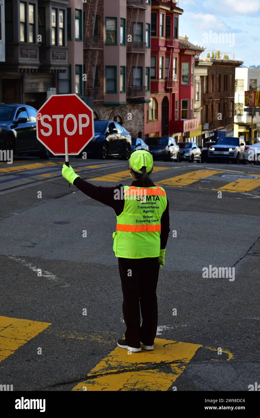 Ein Schulkreuzer, der eine gut sichtbare Jacke trägt und ein Stoppschild auf der Powell Street in der Innenstadt von San Francisco hält Stockfoto