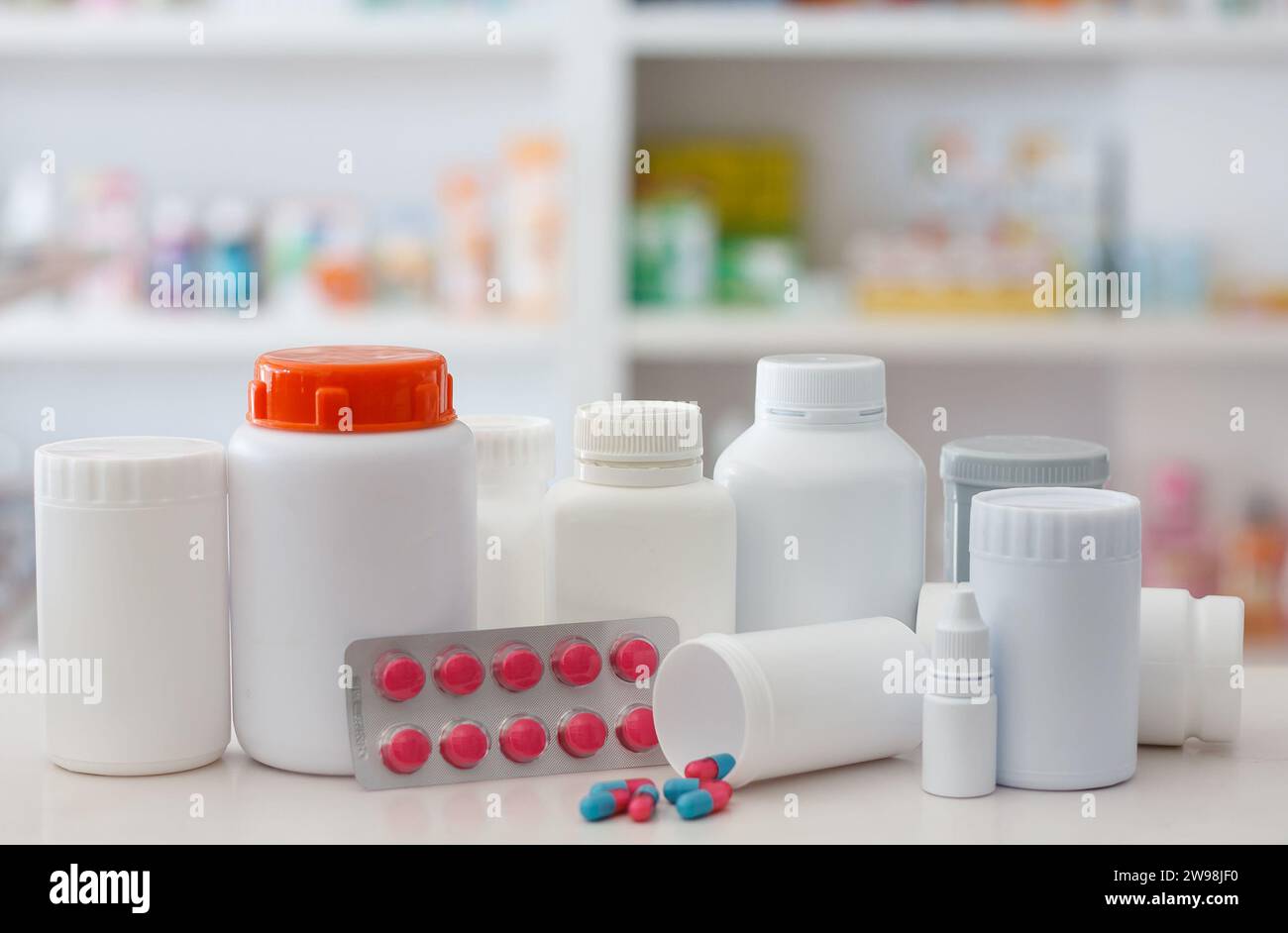 Zusammensetzung von Arzneimittelflaschen und Pillen mit Apothekenregalen im Hintergrund Stockfoto