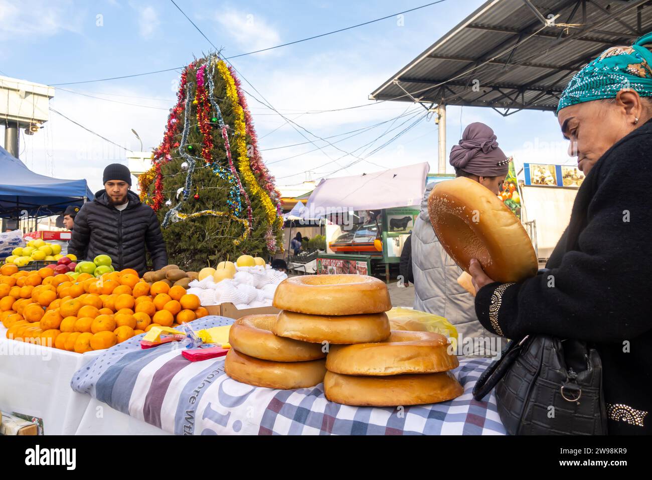 Usbekische Frau kauft traditionelles usbekisches Rundbrot an den Ständen von Siyob oder Siob Basar mit einem Weihnachtsbaum Samarkand Usbekistan Stockfoto