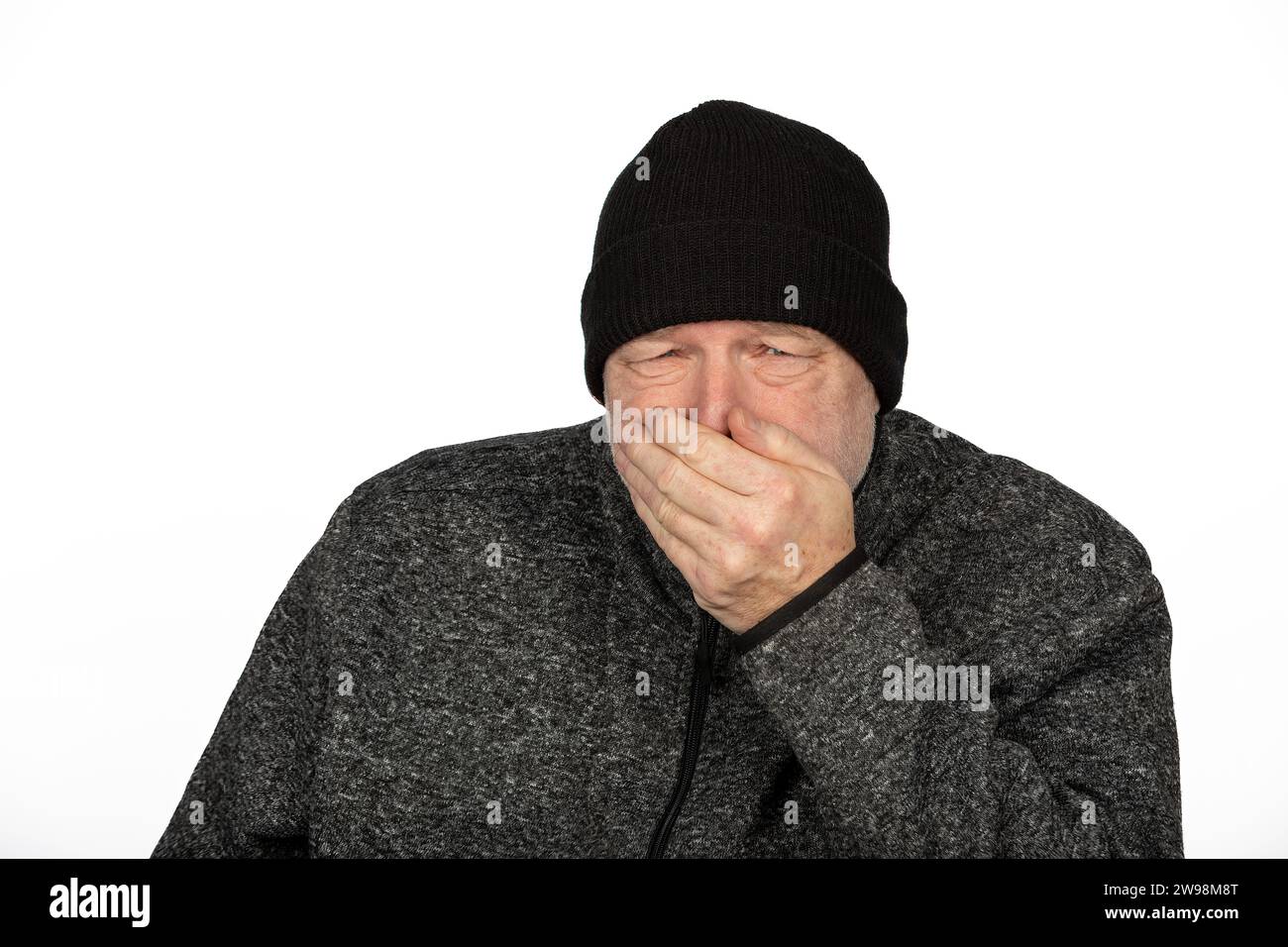 Kaukasischer Mann mittleren Alters in schwarzem Winterhut, der auf weißem Hintergrund friert Stockfoto