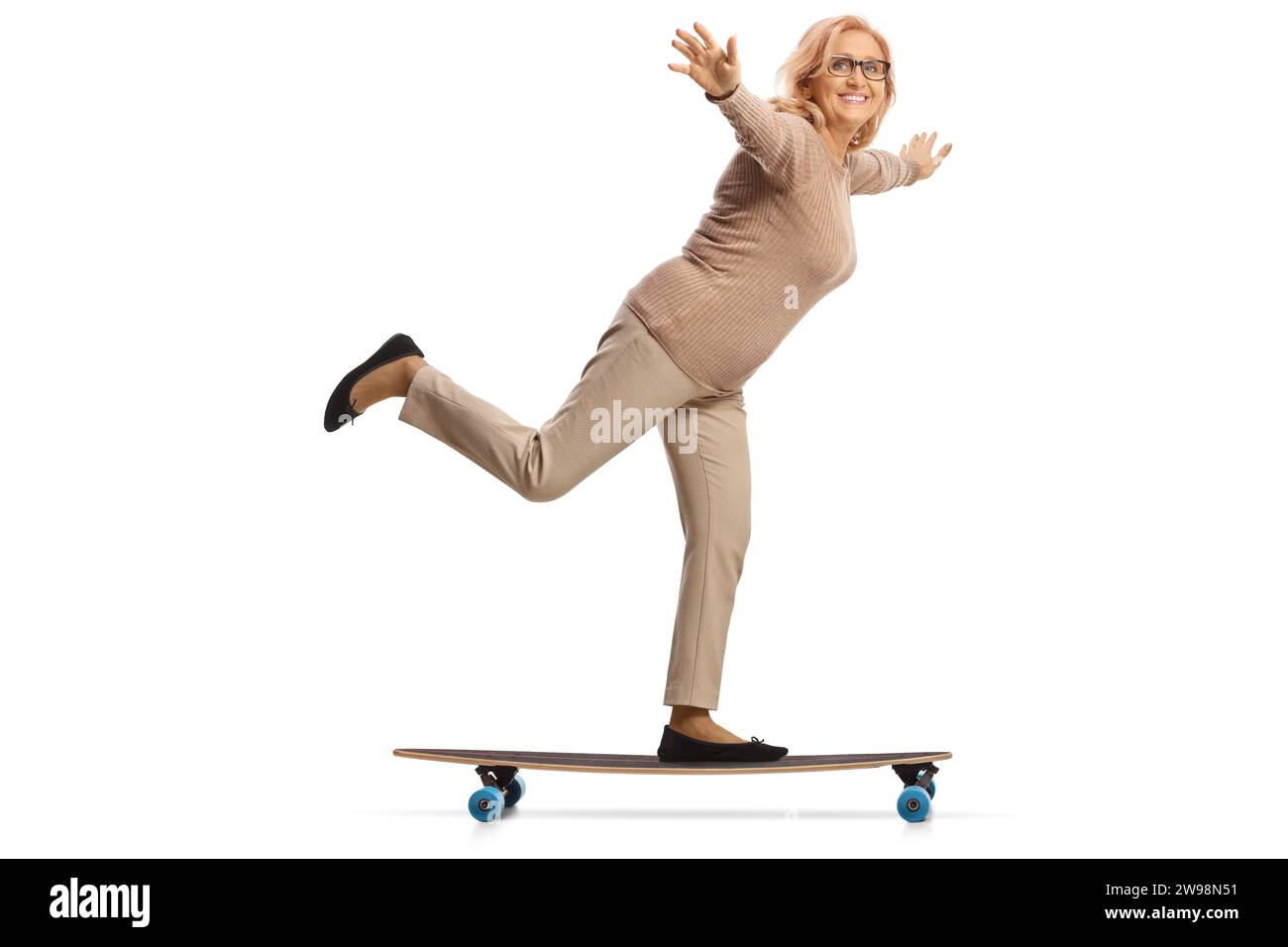 Aufnahme in voller Länge einer Frau mittleren Alters, die auf einem Skateboard fährt und Arme ausbreitet, isoliert auf weißem Hintergrund Stockfoto