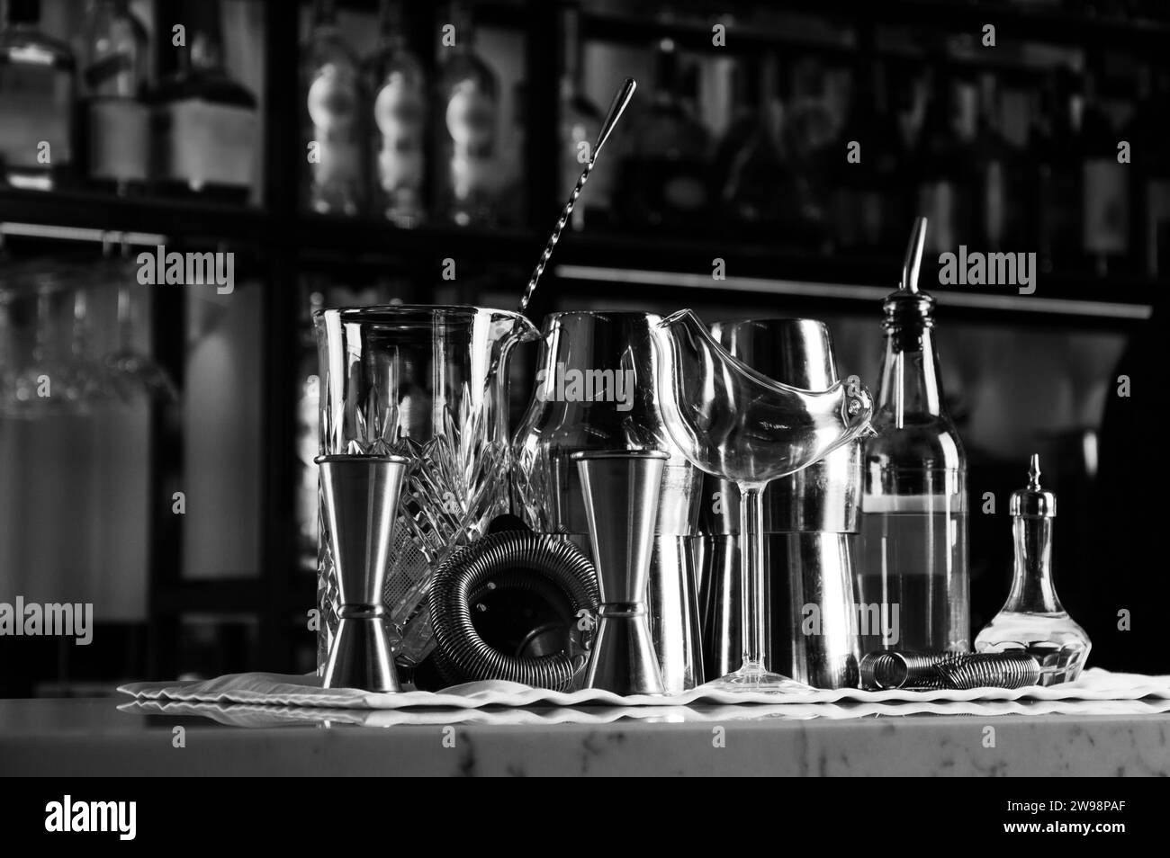 Bar-Accessoires für die Zubereitung von Cocktails, hinter der Bar befindet sich ein Regal mit Likören und starkem Alkohol. Gemischte Medien Stockfoto