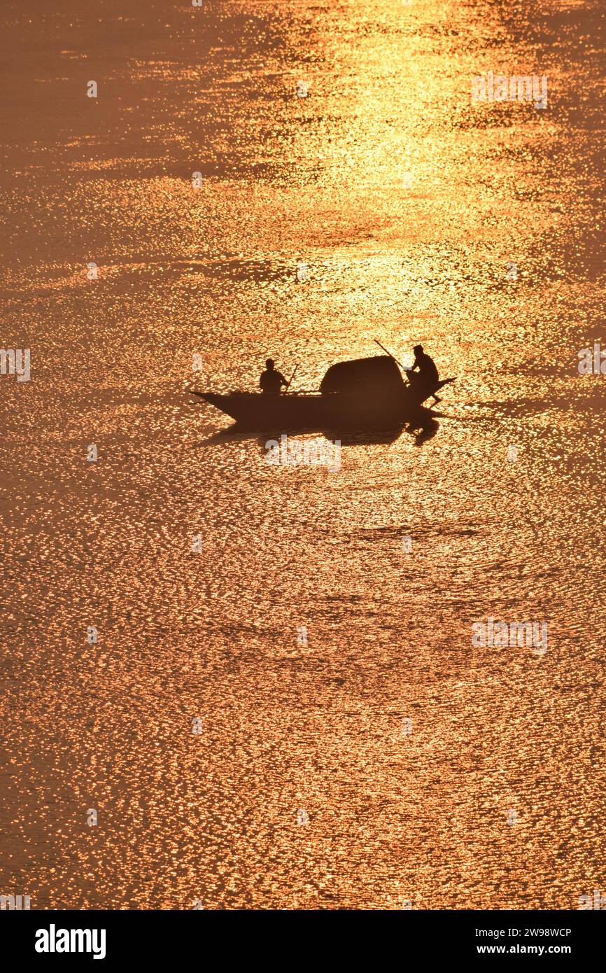 Ein Boot auf dem goldenen Fluss. Fischer fischen im Fluss bei Sonnenaufgang. Stockfoto