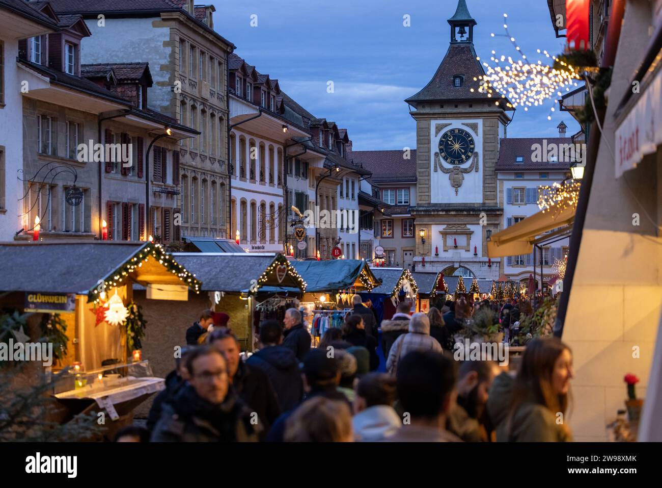 Eine lebhafte Straßenszene bei Nacht, in der die Leute an Weihnachten um die geschmückten Buden herumschleifen. Stockfoto