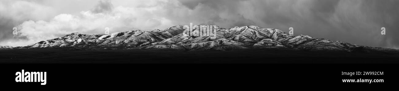 Ein dramatisches Schwarz-weiß-Foto, das einen majestätischen Berg unter einem stürmischen Himmel zeigt Stockfoto