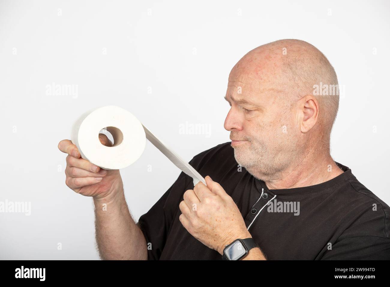 Skurriler Wahnsinn: Mann mittleren Alters, der Toilettenpapierrolle auf weißem Hintergrund hält Stockfoto