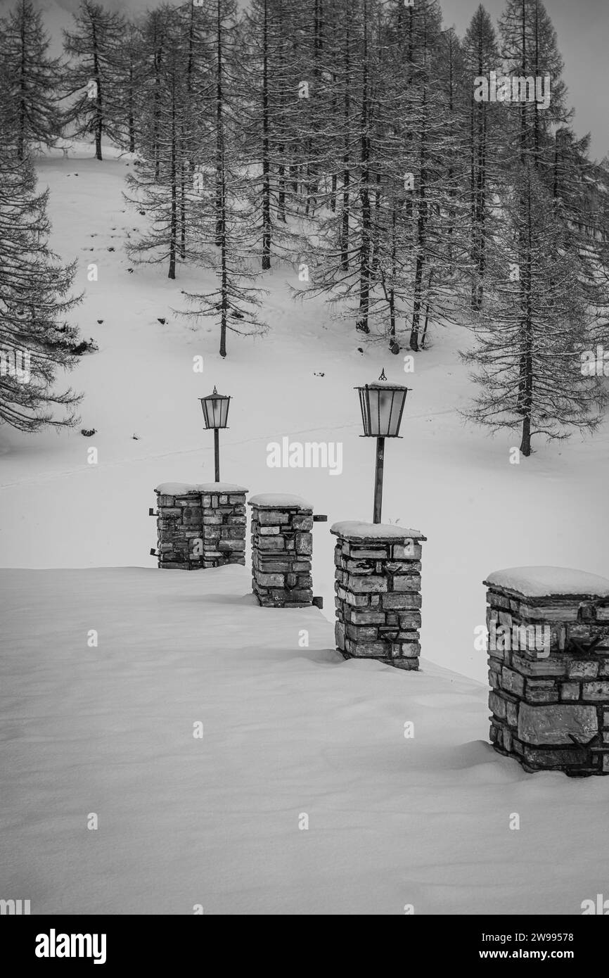 Eine vertikale aus Steinsäulen mit Lampen auf einer Veranda gegen eine Kiefer im Schnee im Winter Stockfoto