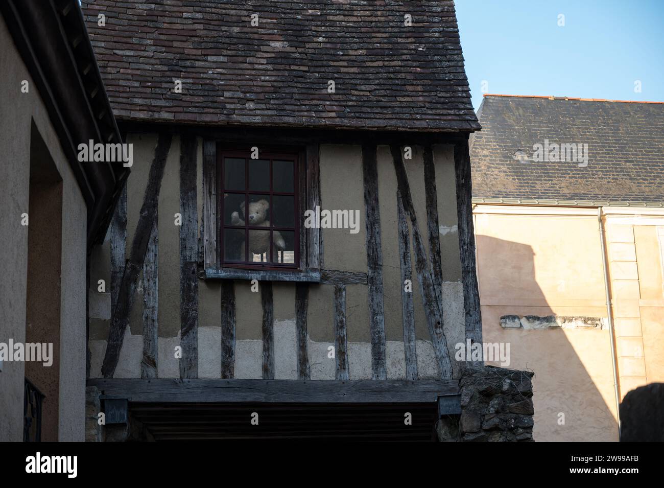 Detail des malerischen und wunderschönen hängenden Hauses von Le Mans Klon eines Teddybären, der durch das Fenster winkt Stockfoto