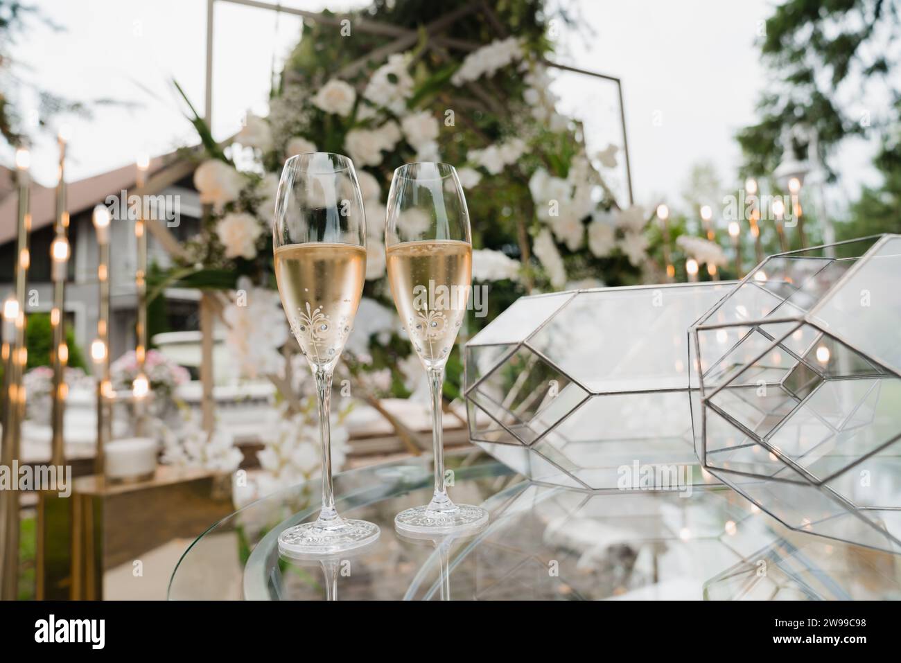 Drei elegante Gläser Rotwein auf einem weiß gekleideten Tisch im Garten, perfekt für eine Hochzeitsfeier Stockfoto