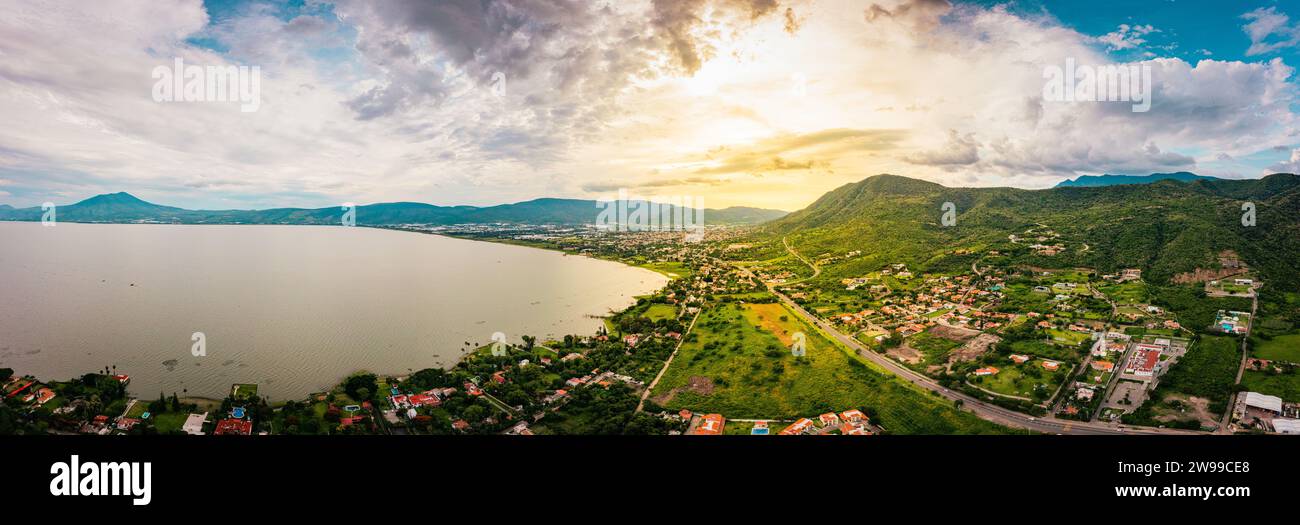Ein Panorama der Berge und des Sees mit dem Sonnenuntergang als Hintergrund. Wolken und blauer Himmel mit Bäumen und Farben Stockfoto