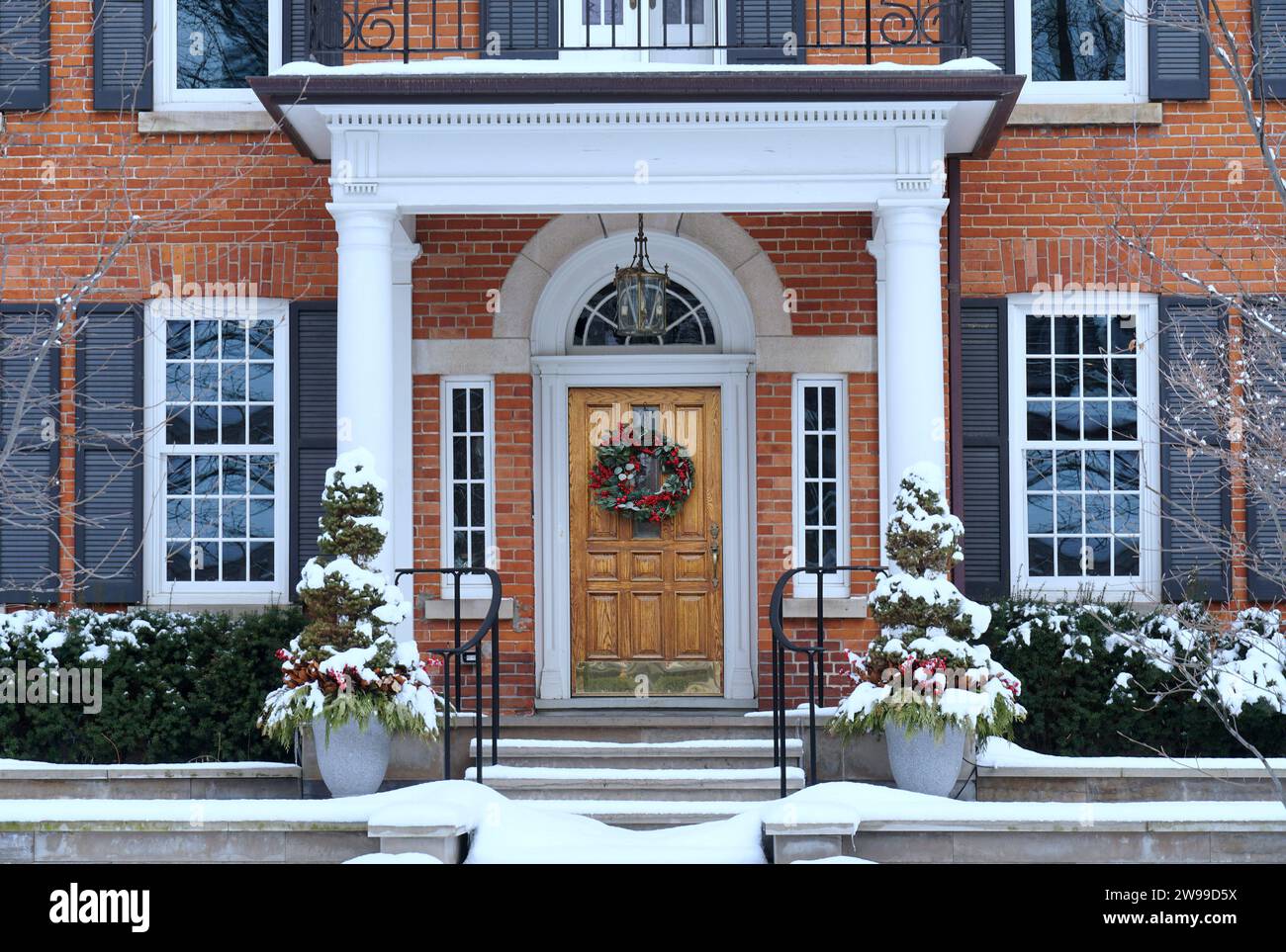 Haus im Winter mit eleganter Holzmaserung Eingangstür mit Weihnachtskranz Stockfoto