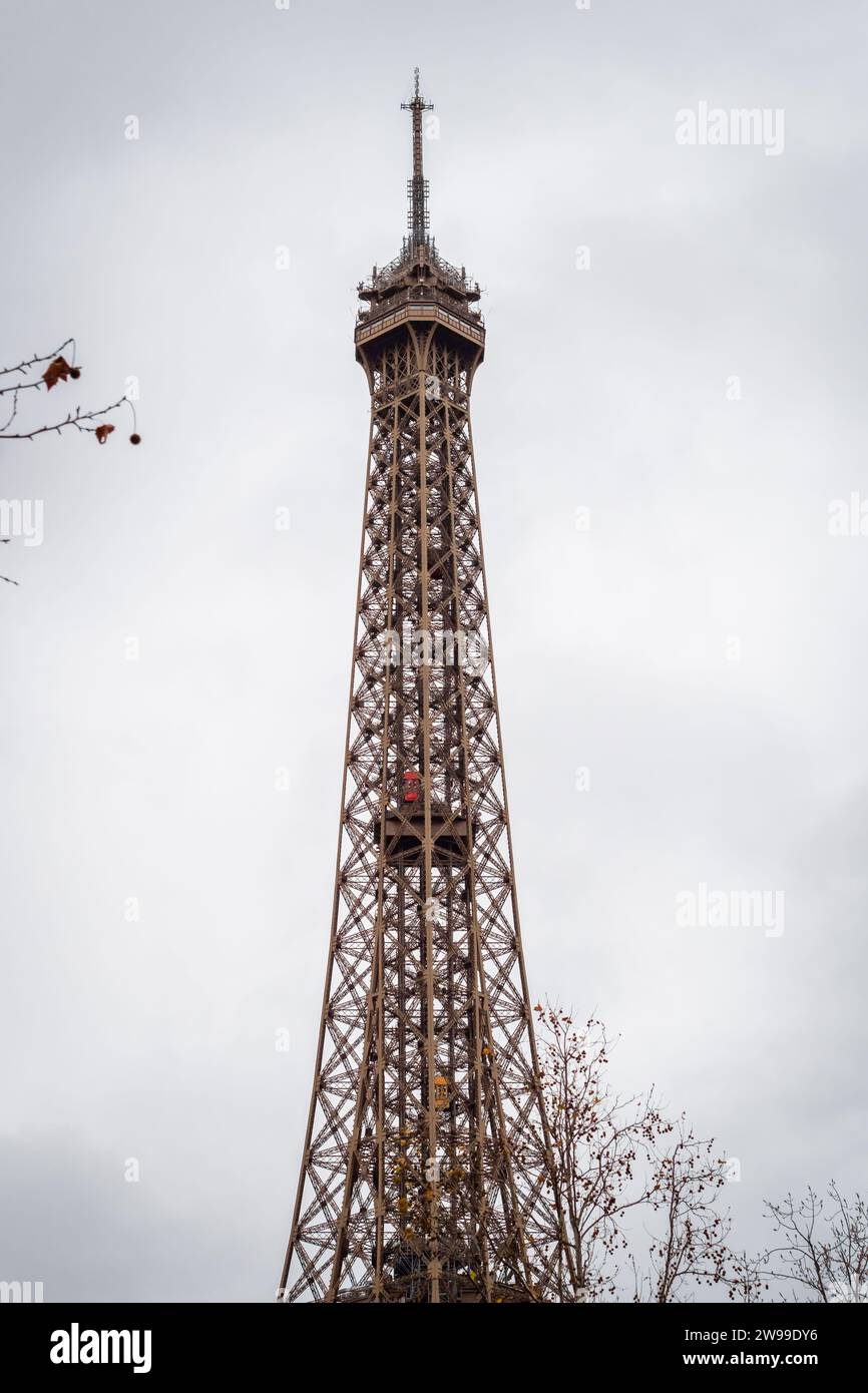 Herbstzweige auf dem Eiffelturm in Paris mit seinem aufsteigenden roten Aufzug - Frankreich Stockfoto