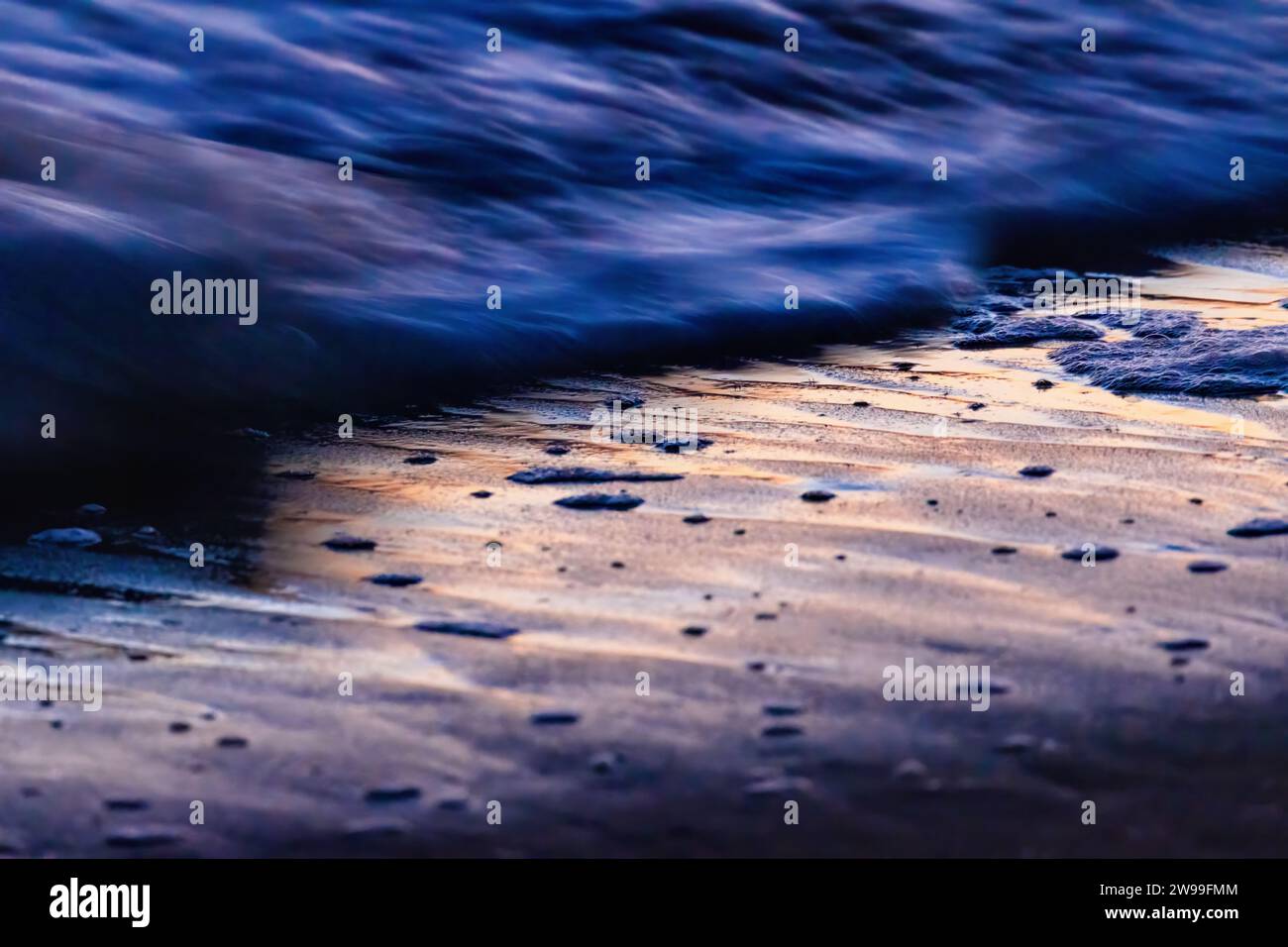 Eine malerische Strandszene bei Sonnenuntergang mit Wellen, die auf die Küste Rollen, schaffen eine ruhige Atmosphäre Stockfoto