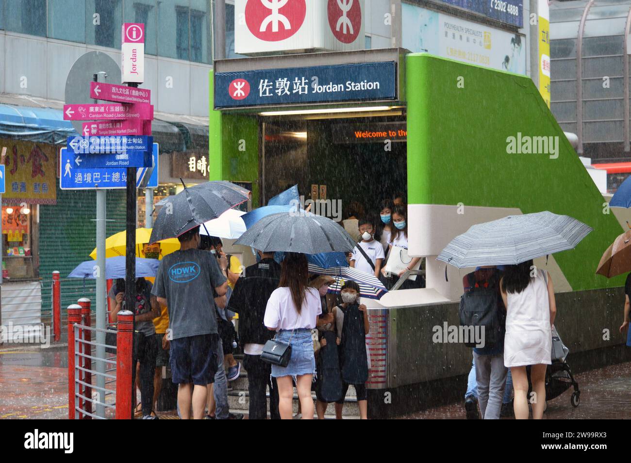 Fußgänger mit Regenschirmen am Ausgang C2 der Jordan Station, einer MTR-Station in der Gegend von Kwun Chung in Kowloon, Hongkong, bei starkem Regen (2021) Stockfoto