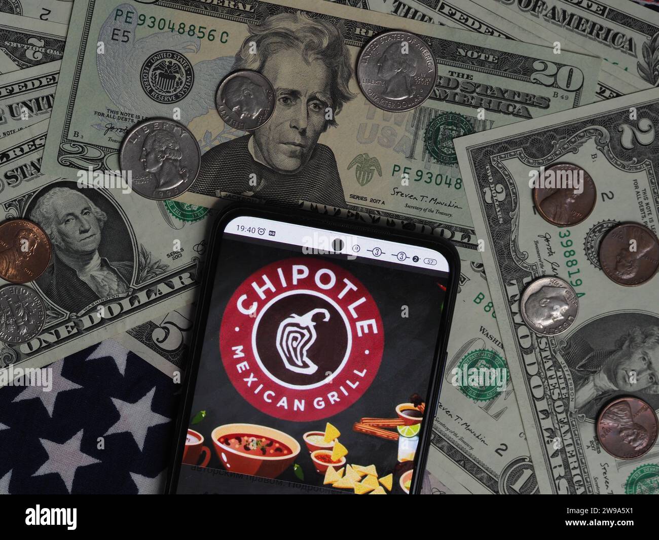 Deutschland. Dezember 2023. In dieser Fotoabbildung ist ein Chipotle Mexican Grill-Logo auf einem Smartphone mit US-Dollar-Banknoten und -Münzen im Hintergrund zu sehen. (Foto von Igor Golovniov/SOPA Images/SIPA USA) *** ausschließlich für redaktionelle Nachrichten *** Credit: SIPA USA/Alamy Live News Stockfoto