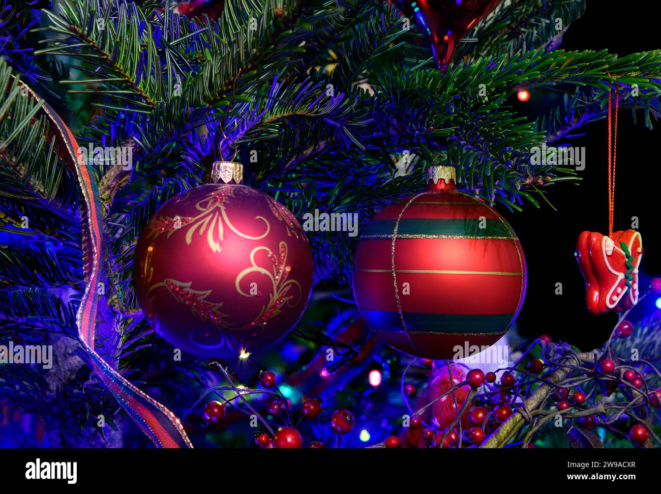 Nahaufnahme der festlichen Weihnachtsdekoration, die an einem beleuchteten Weihnachtsbaum hängt. Stockfoto