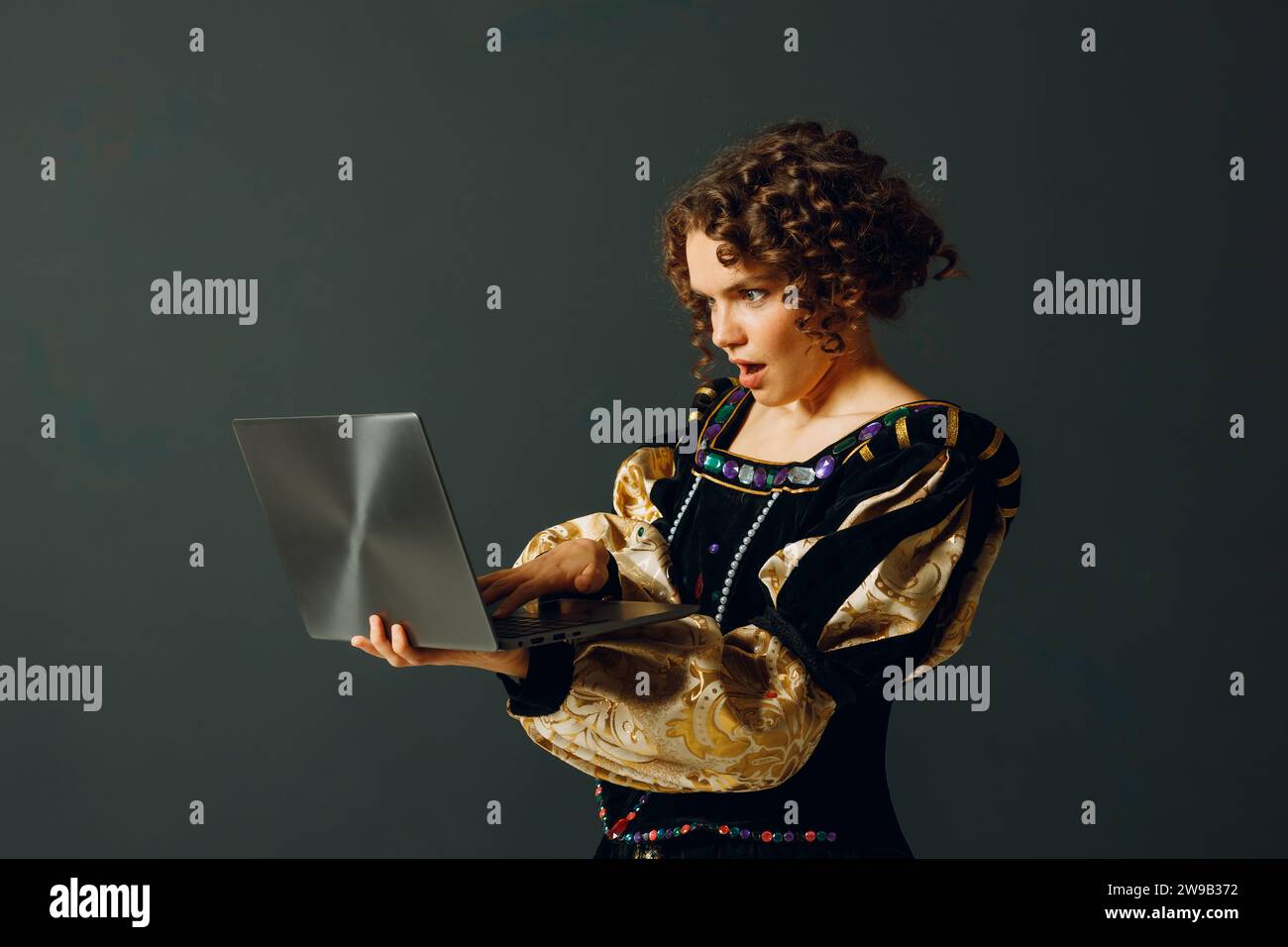 Porträt einer jungen Aristokratin in einem mittelalterlichen Kleid, die am Laptop arbeitet Stockfoto