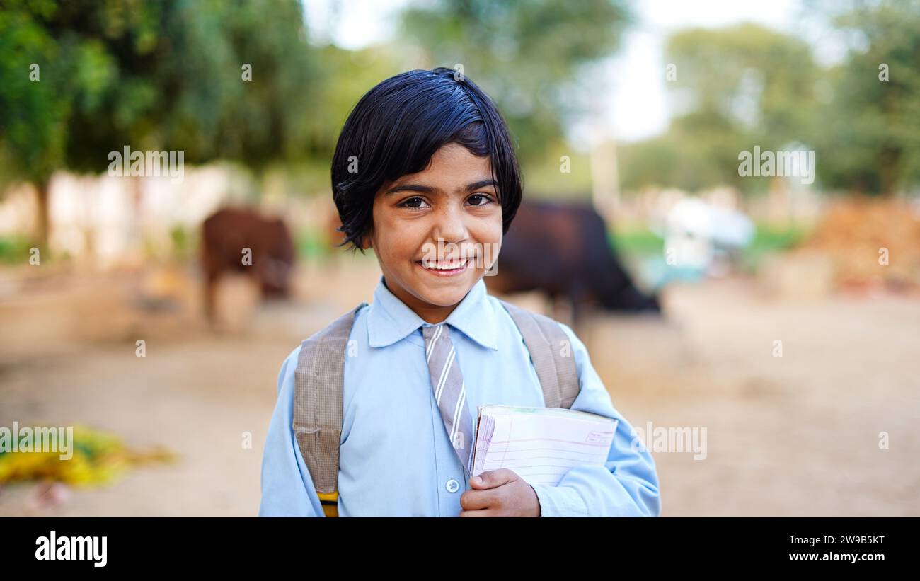 Lächelnde Schülerin mit Schulrucksack und Lehrbuch. Porträt eines glücklichen asiatischen Dorfes vor Haustieren. Das Gesicht der lächelnden Schule Stockfoto