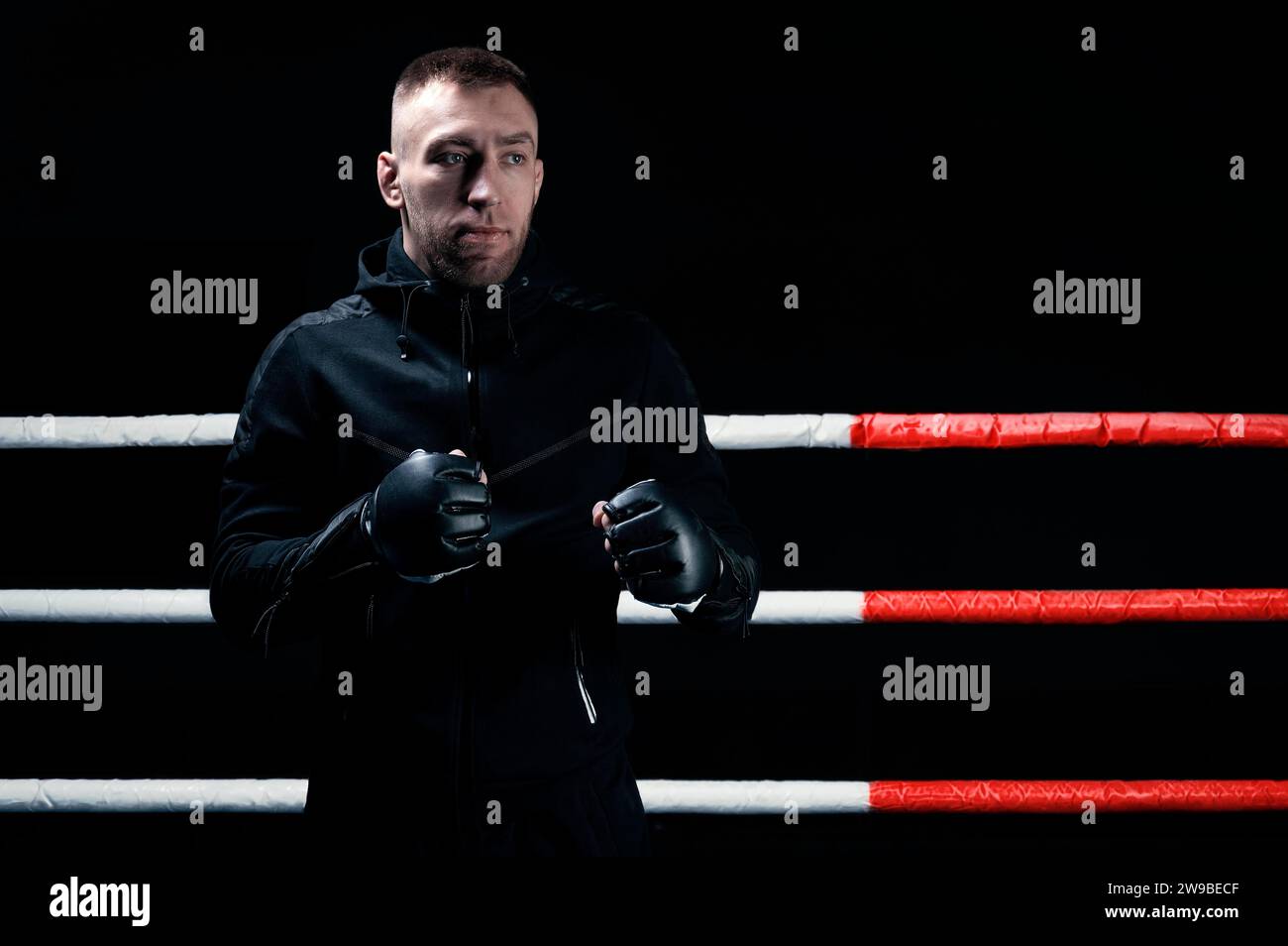 Ein gemischter Kampfkünstler steht mit erhobenen Händen. Konzept von mma, ufc, thai-Boxen, klassischem Boxen. Gemischte Medien Stockfoto