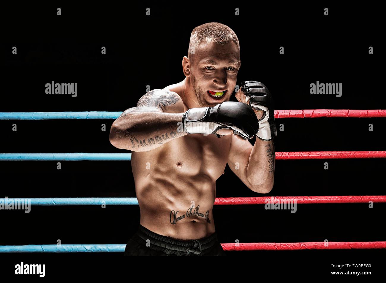 Gemischter Kampfkünstler posiert im Boxring. Konzept von mma, thai-Boxen, klassisches Boxen. Gemischte Medien Stockfoto