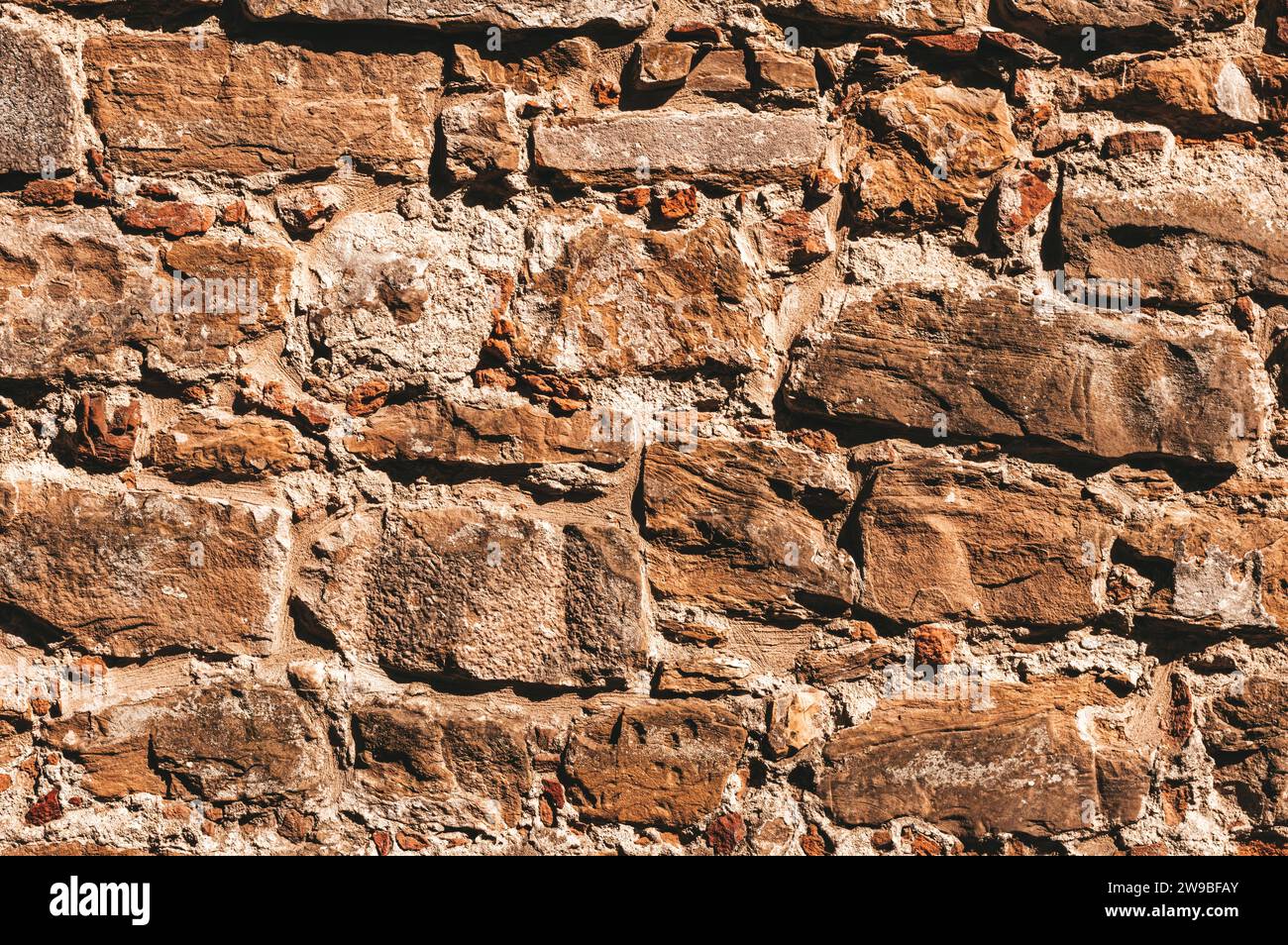 Tapete einer Steinmauer. Antike, leicht zerstörte Steine. Florenz. Gemischte Medien Stockfoto