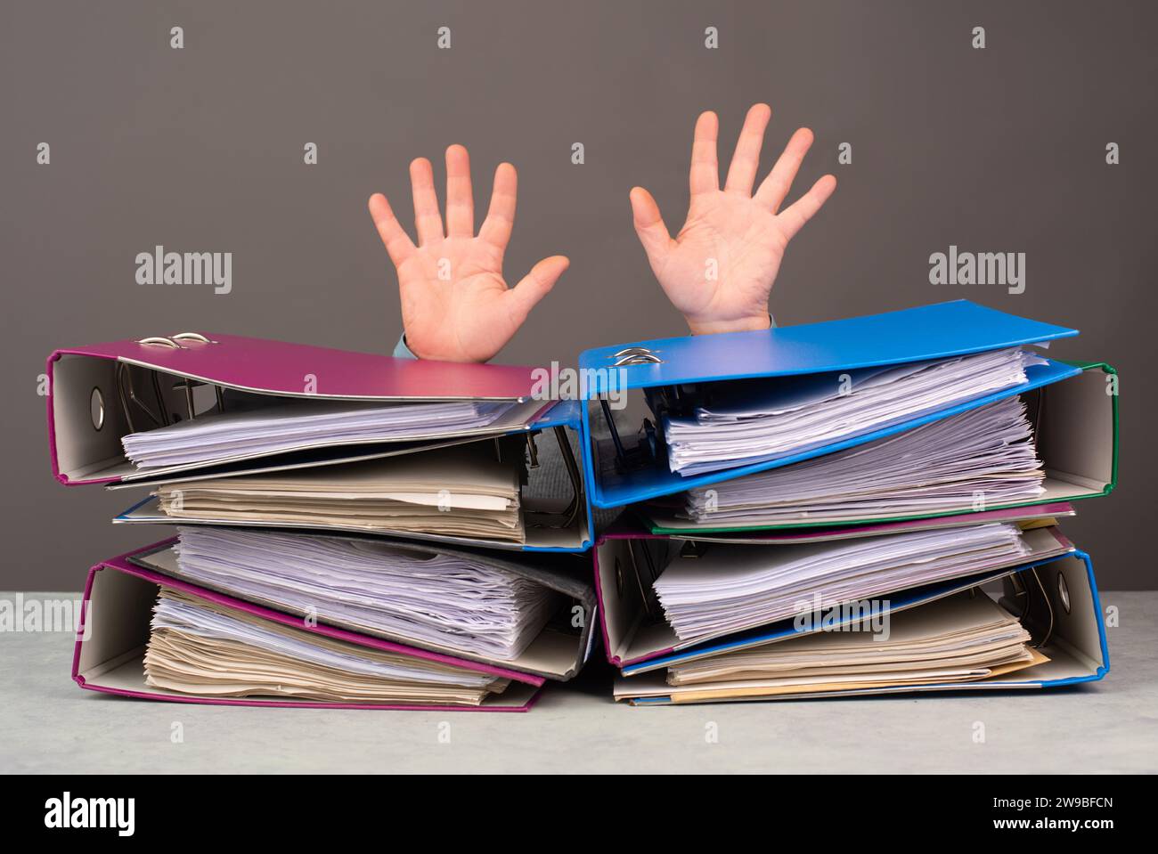 Erschöpfte, müde Arbeiter, Haufen Aktenordner, Hände hoch, Burnout, Stress und Überlastung, Druck bei der Arbeit Stockfoto