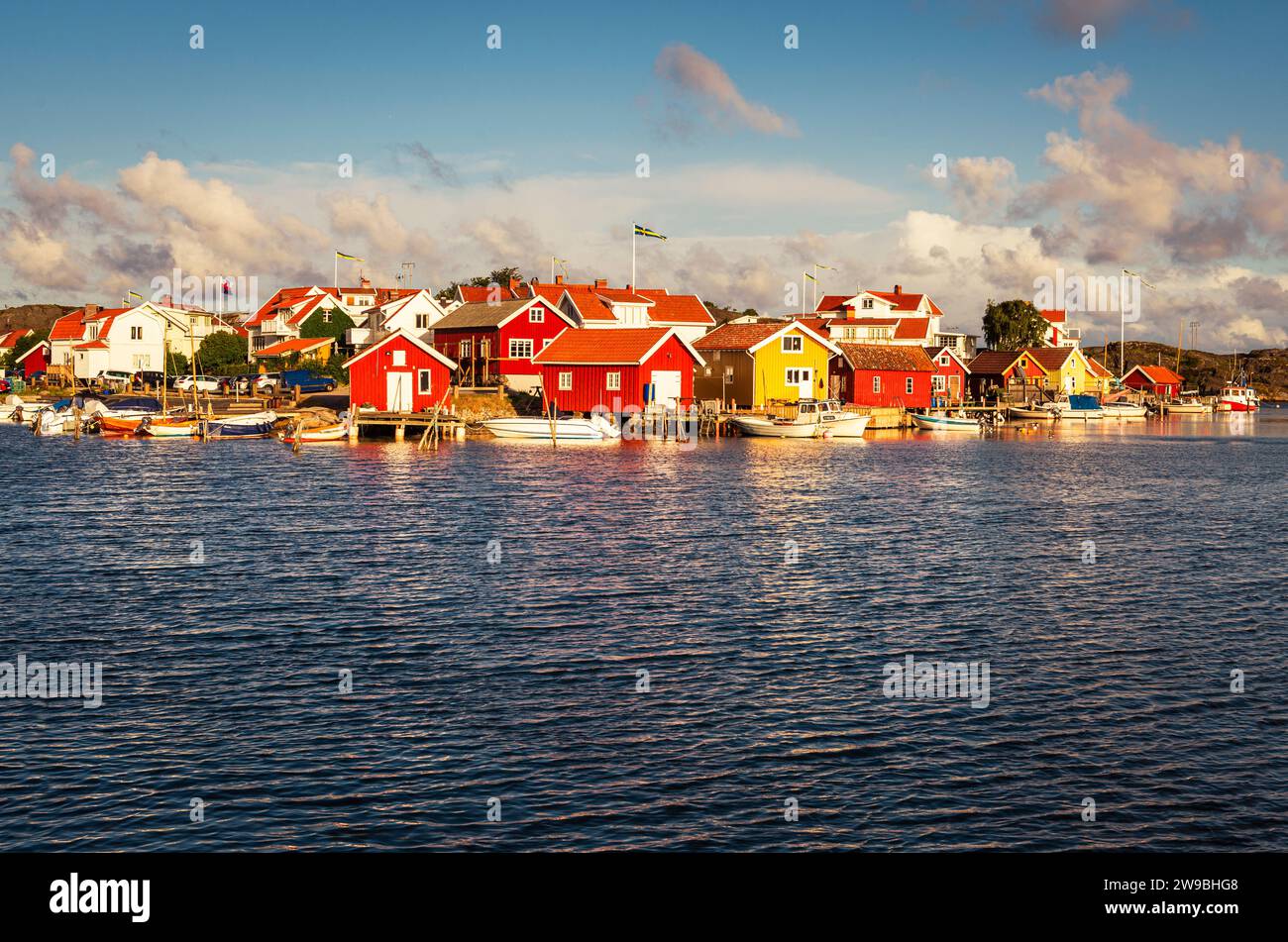 Sonnenaufgang über den bunten Holzhäusern im Hafen von Björholmen auf der Insel Tjörn im Archipel der Westküste Schwedens Stockfoto