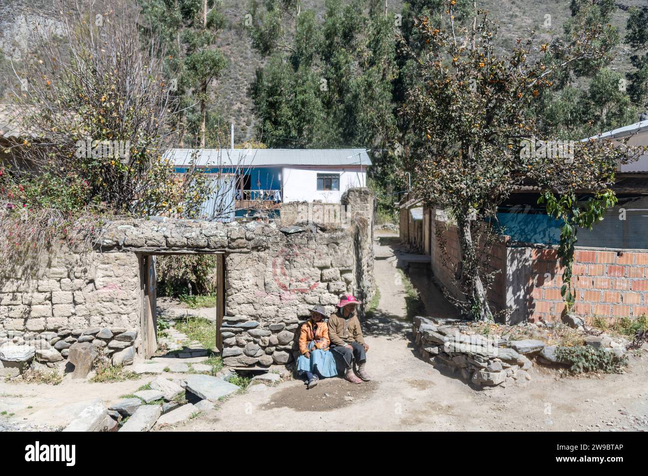 Zwei einheimische Peruaner saßen an einer Mauer in einem Dorf in den Anden in Peru Stockfoto