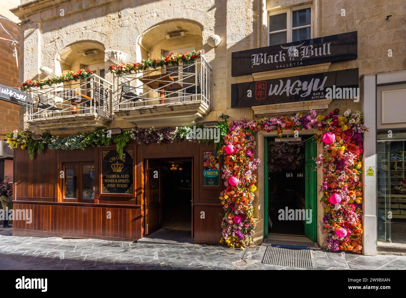 Ein mit bunten Blumengirlanden geschmückter Eingang führt zur Bar "Black Bull Valletta" und zum Restaurant "Wagyu Bar & Kitchen" in Valletta, Malta. Stockfoto