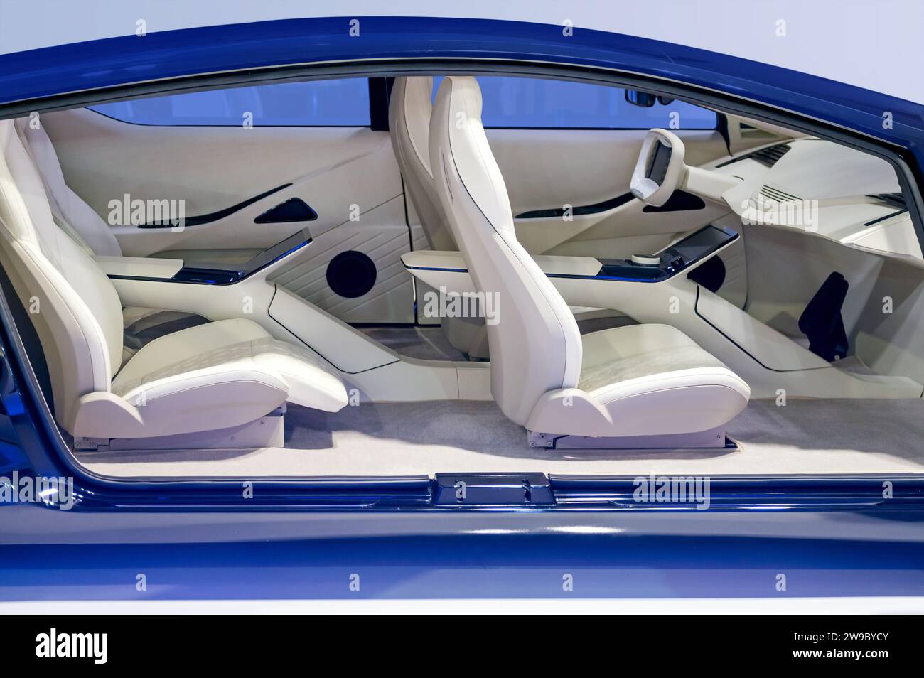Seitenansicht des futuristischen Fahrzeuginnenraums mit gemütlichen Sitzen mit Kopfstützen in blauer Karosserie und Armaturenbrett, das das Lenkrad im Werk bei Licht ersetzt Stockfoto