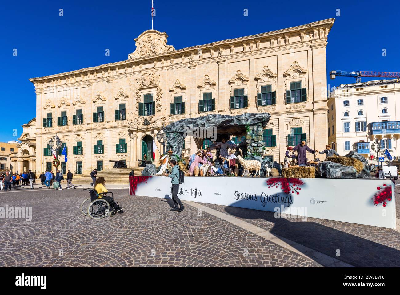 Eine große Weihnachtskrippe mit der Aufschrift „Seasons Greetings“ steht vor Il-Berġa ta' Kastilja (Auberge de Castille), dem offiziellen Wohnsitz des Premierministers von Malta in Valletta. Andrea Belli baute das Gebäude, das ursprünglich 1573/74 erbaut wurde, zwischen 1741 und 1744 im spanischen Barockstil um, beauftragt vom Großmeister Manuel Pinto da Fonseca. Presepju, die maltesische Krippentradition, erreichte ihren Höhepunkt im 19. und frühen 20. Jahrhundert, wurde später vom Weihnachtsbaum in den Schatten gestellt und seit 1986 von der Gesellschaft der Freunde der Krippe wiederbelebt. Stockfoto