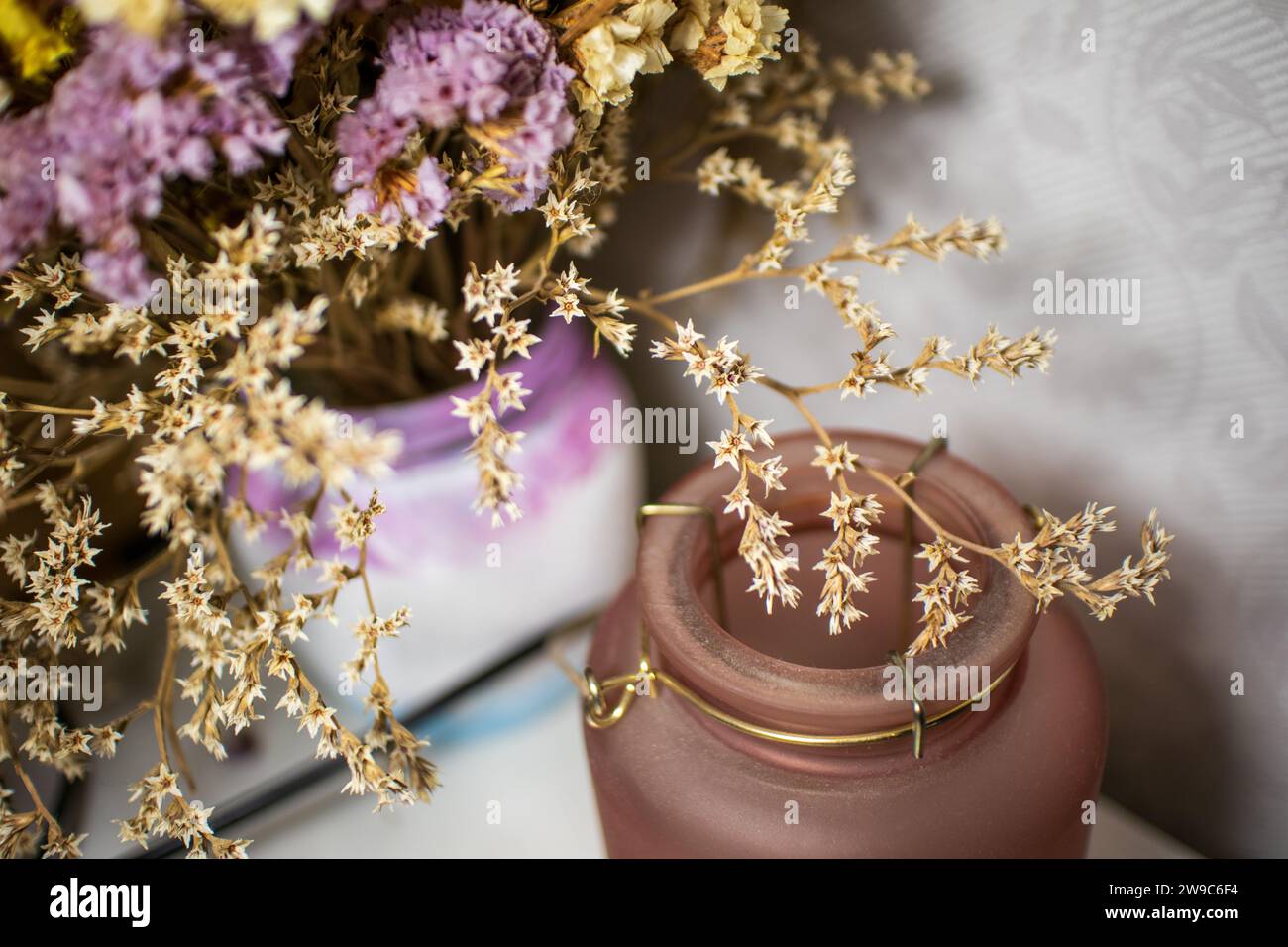 Nahaufnahme von blühenden lila, weißen und gelben kleinen Blüten in Vase. Getrocknete Blumen oder Ikebana für die Innendekoration. Stockfoto