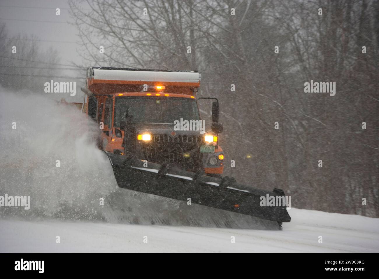 Der schwere Schneepflug räumt eine Landstraße während eines Winterblizzards in den grünen Bergen von Vermont Stockfoto