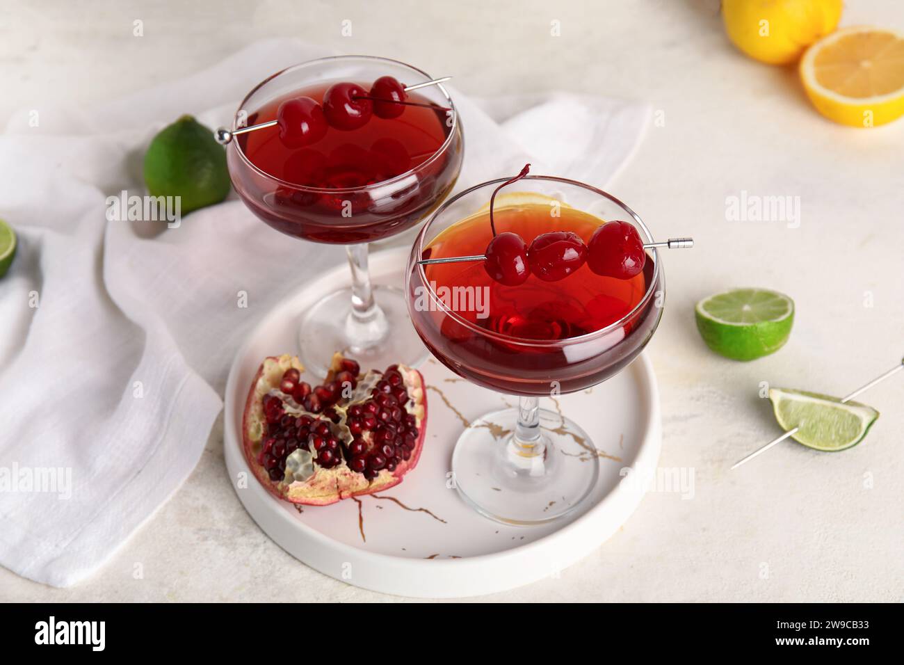 Gläser Cosmopolitan Cocktail mit Kirschen und Granatapfel auf weißem Hintergrund Stockfotografie