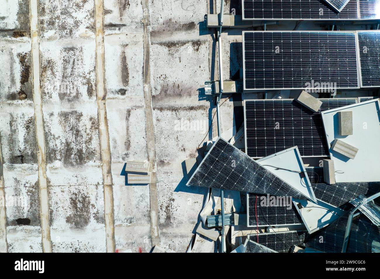 Draufsicht der durch den Hurrikan Ian zerstörten Photovoltaik-Solarpaneele, die auf dem Dach des Industriebaues zur Erzeugung von ökologischem Strom montiert sind Stockfoto