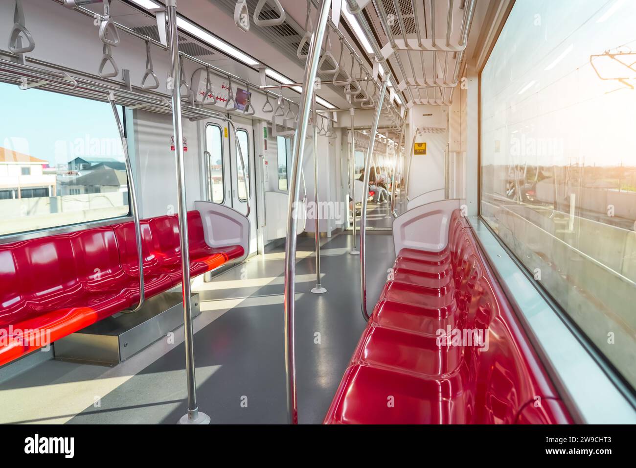 Rote Kunststoffsitze und Chrom-Handläufe in einem elektrischen Zugwagen. Stockfoto