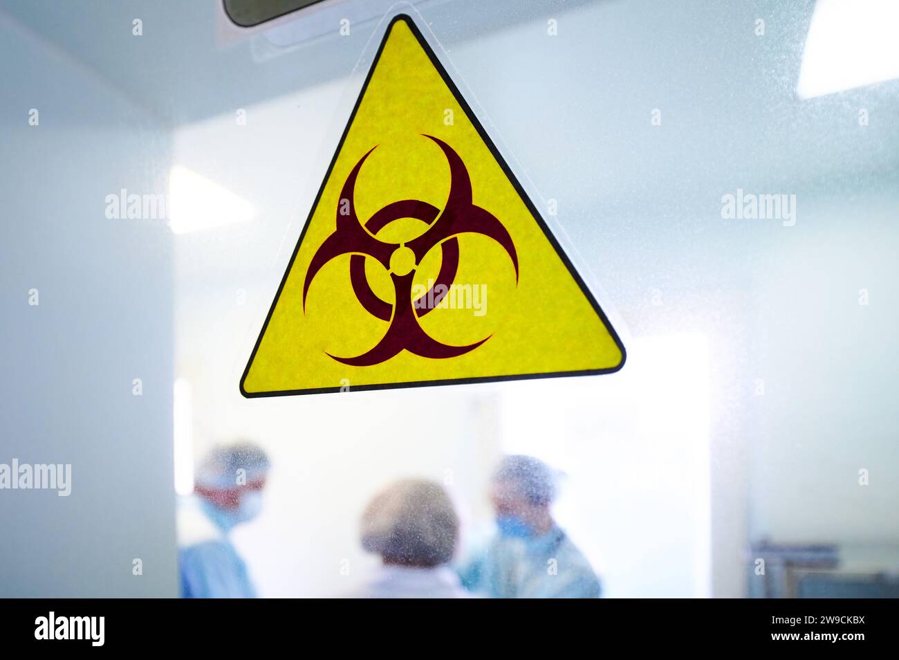 Warnschild „Biogefährdung“ auf durchsichtiger Labortür Stockfoto