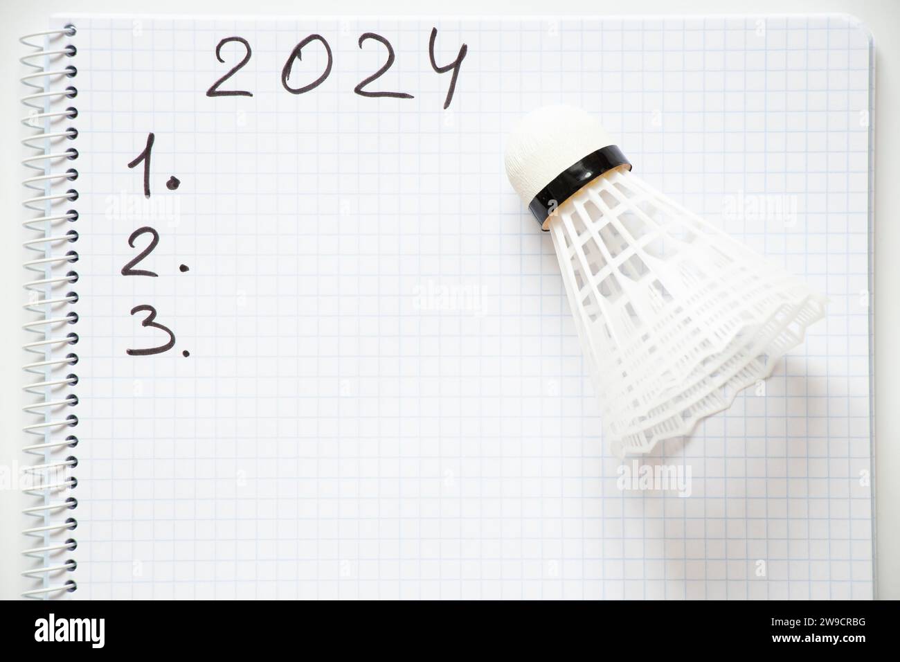 2024 und die Zahlen 123 sind in einem Notizbuch geschrieben und daneben liegt ein Shuttlecock auf weißem Hintergrund, der das neue Jahr plant Stockfoto