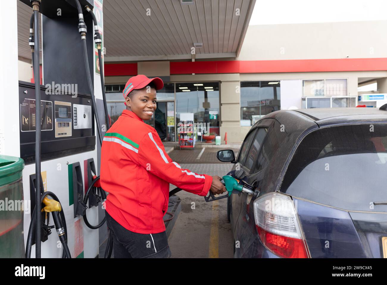 afroamerikanischer Benzinwächter, der an der Tankstelle Auto betankt Stockfoto