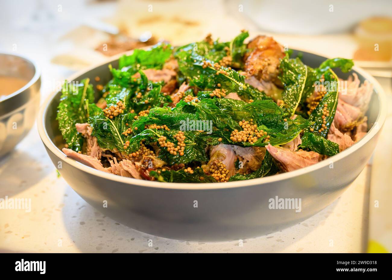 Lammbraten mit Minze und Senfsamen in einer Schüssel auf dem Küchentisch. Hausmannskost und Unterhaltungskonzept. Stockfoto