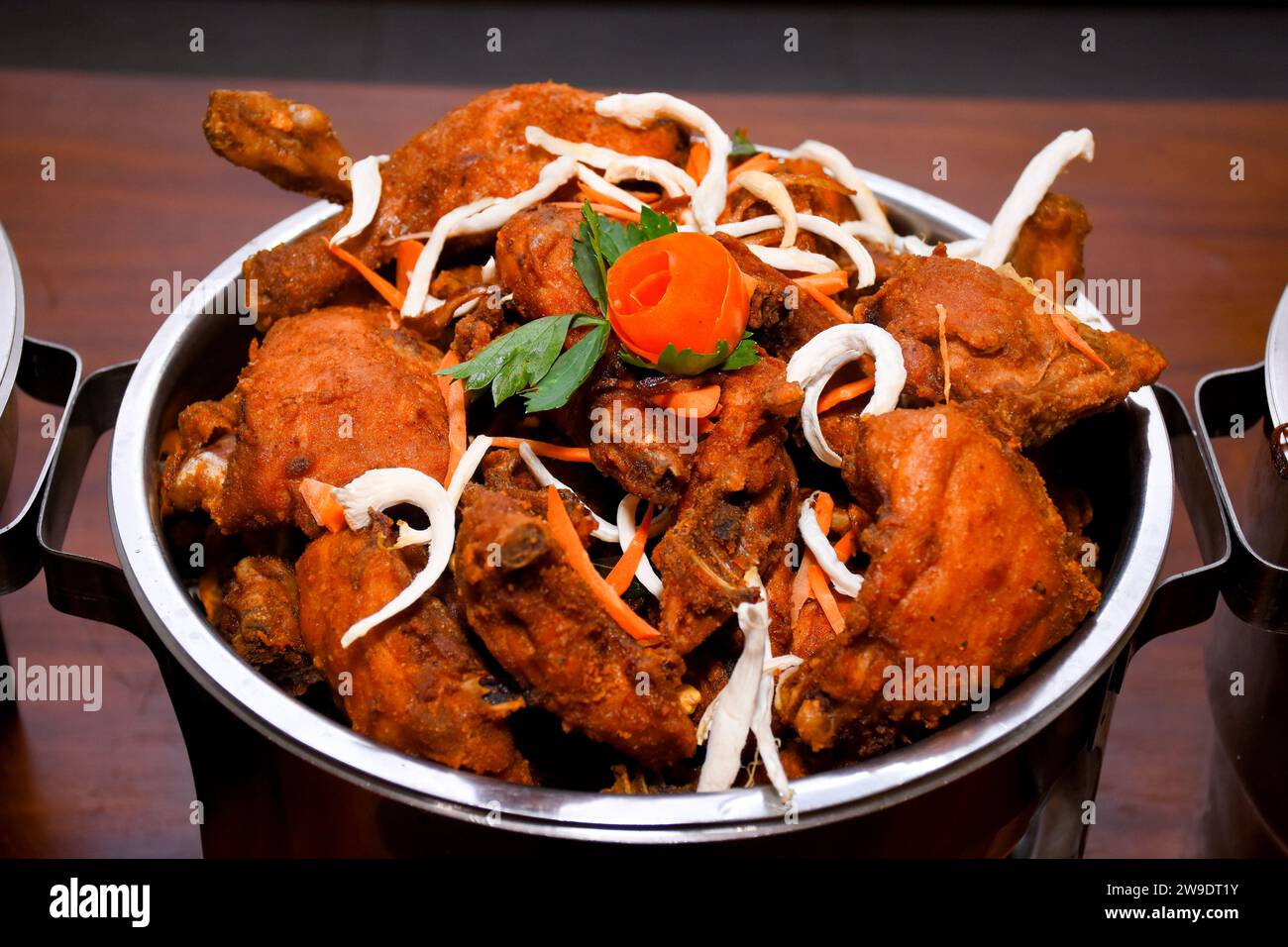 Leckeres Butter-Hühnchen-Curry-Gericht aus indischer Küche in Buffet, Orangenscheiben-Dekorationen. Stockfoto