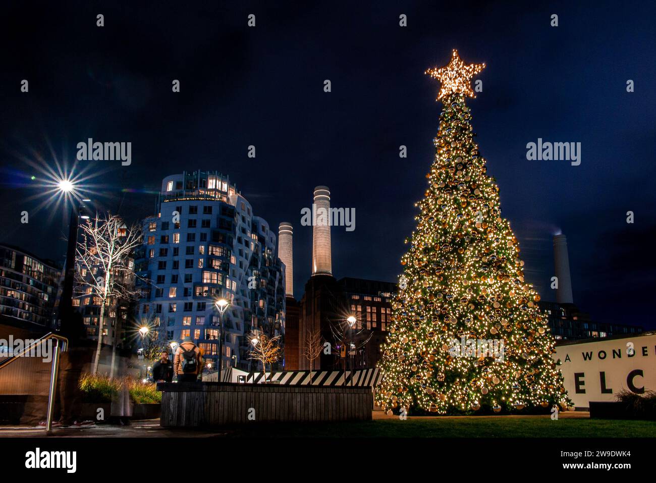 Weihnachtslichter und ein Weihnachtsbaum vor dem berühmten Kamin der Battersea Power Station bei Nacht Stockfoto