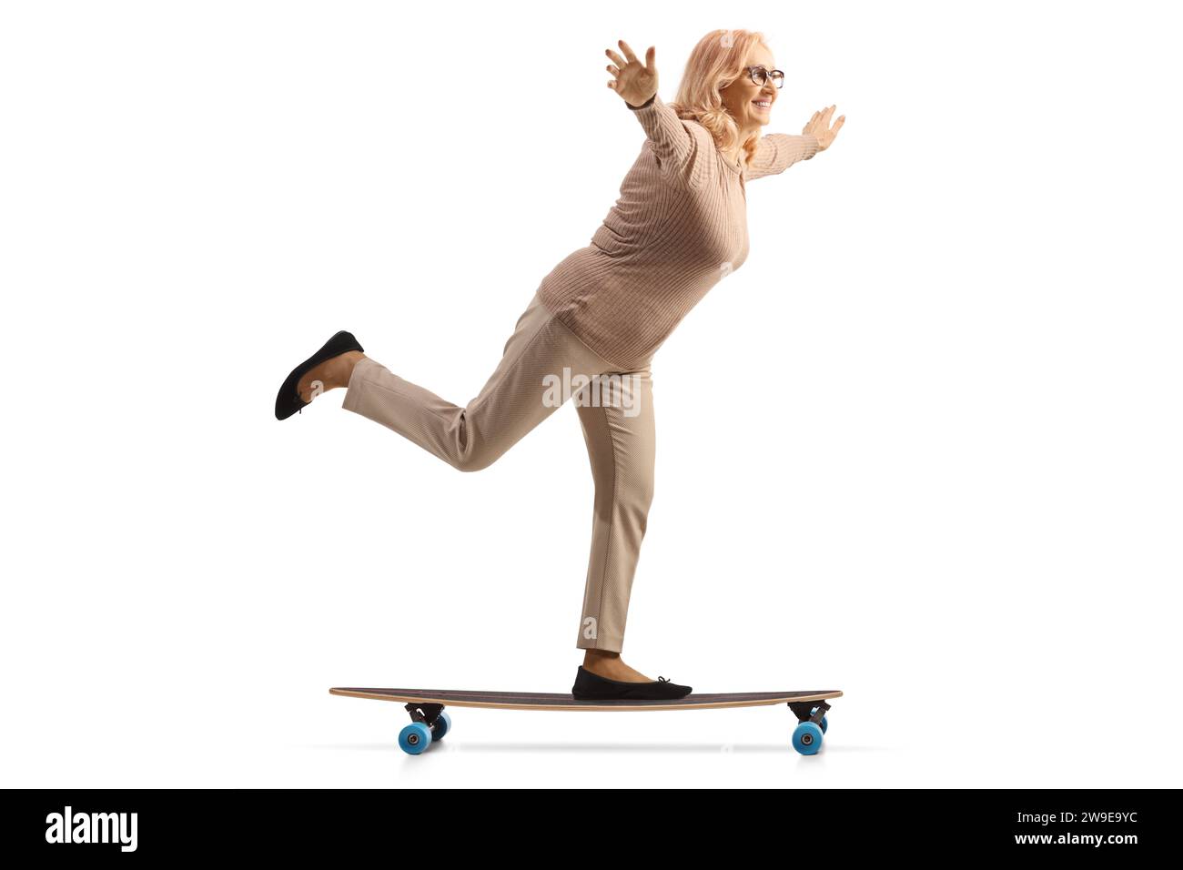 Frau mittleren Alters, die Skateboard fährt und Arme auf weißem Hintergrund verteilt Stockfoto