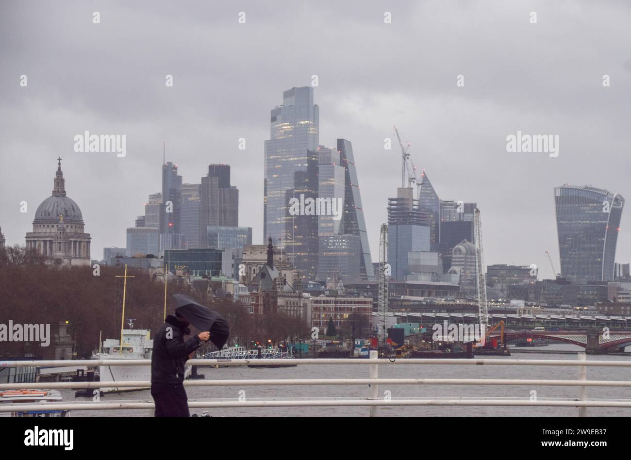 London, England, Großbritannien. Dezember 2023. Ein Preußer läuft über die Waterloo Bridge vorbei an der Skyline der City of London, dem Finanzviertel der Hauptstadt, und stürzt bei starkem Wind und Regen, wenn Storm Gerrit das Vereinigte Königreich trifft. (Kreditbild: © Vuk Valcic/ZUMA Press Wire) NUR REDAKTIONELLE VERWENDUNG! Nicht für kommerzielle ZWECKE! Stockfoto