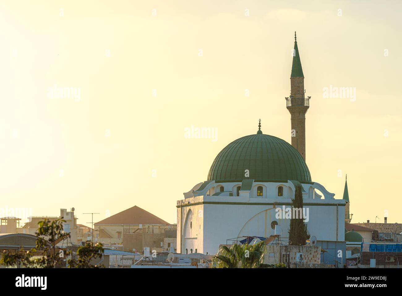 Ein islamisches Gebäude, eine Moschee, erhebt sich aus den Gebäuden mit Minarett und Kuppel zur goldenen Stunde Stockfoto