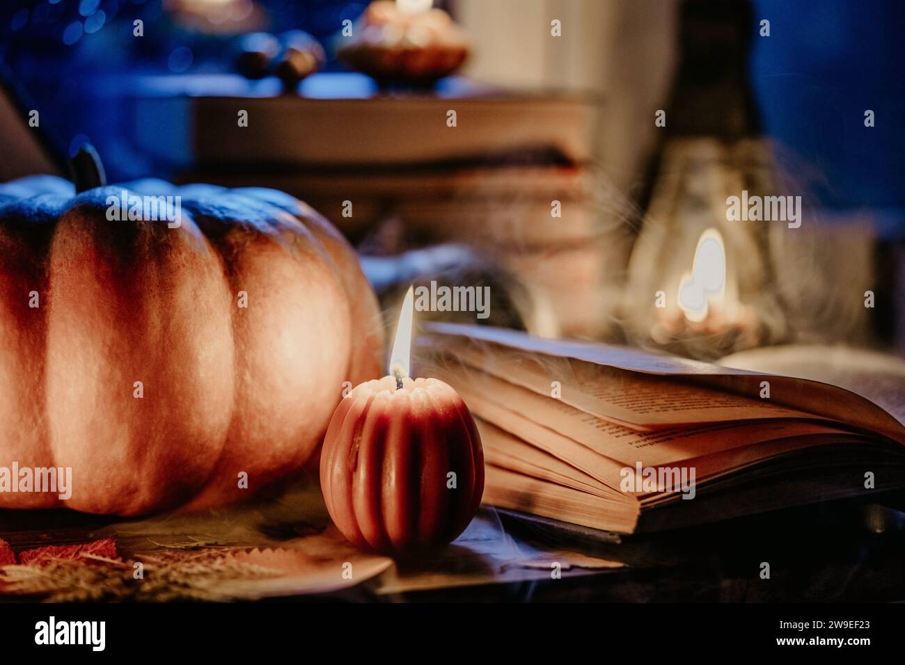 Herbst Hintergrund. Kürbiskerzen brennen, Buch öffnen. Ruhige Momente, Hygge Stockfoto