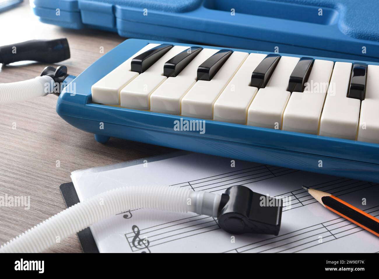 Melodica in seinem Etui mit all seinen Elementen für das Musikstudium mit Noten daneben auf dem Tisch und Bleistift. Erhöhte Aussicht. Stockfoto