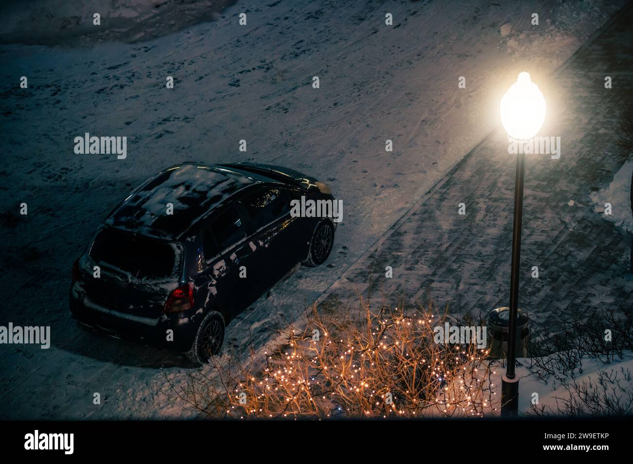 Schwarzes Auto und Laterne auf der Straße im Winter bei Nacht nach Schneefall Stockfoto